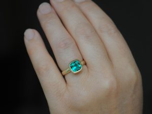 Lab-emerald-8mm-cushion-ring-in-18K-gold-on-hand-2