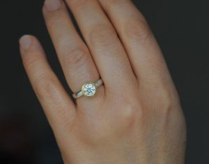 Beautiful and sparkly, this brilliant cut moissanite engagement ring is set in recycled 18K yellow gold with a silver band.