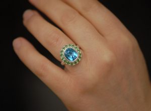 swiss-blue-topaz-halo-ring-with-tsavorite-garnets-in-silver-on-hand-2