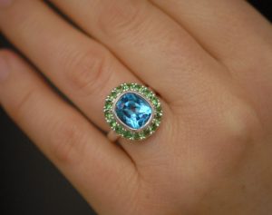 swiss-blue-topaz-halo-ring-with-tsavorite-garnets-in-silver-on-hand