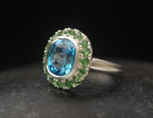 swiss-blue-topaz-halo-ring-with-tsavorite-garnets-in-silver-side-angle