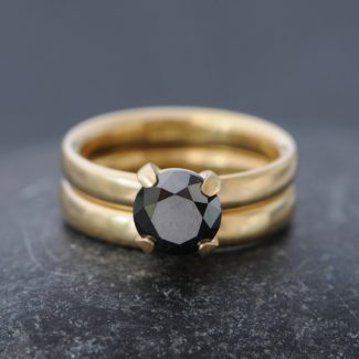 claw set black diamond solitaire in yellow gold engagement ring, with satin finish yellow gold wedding band