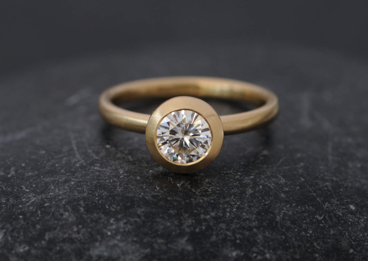 Contemporary solitaire ring featuring Forever Brilliant Moissanite set in 18k gold. By William White