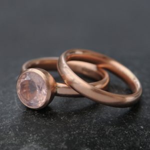 pink rose quartz stone in rose gold engagement ring with matching wedding band