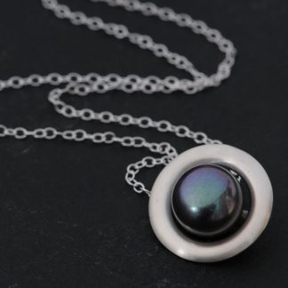 Large Peacock black pearl, set in a satin finished sterling silver halo design. Pearl is 11mm across. Designed and handmade by William White in Cornwall, UK