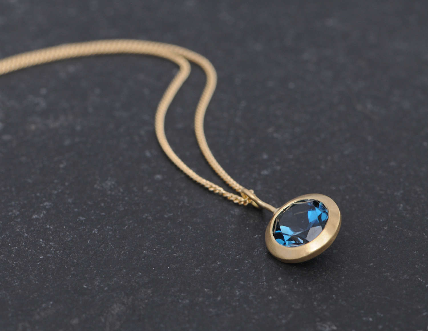 Bright London blue topaz pendant, set in recycled gold on a gold chain. This 18k yellow gold necklace is designed and handmade by William White in Cornwall