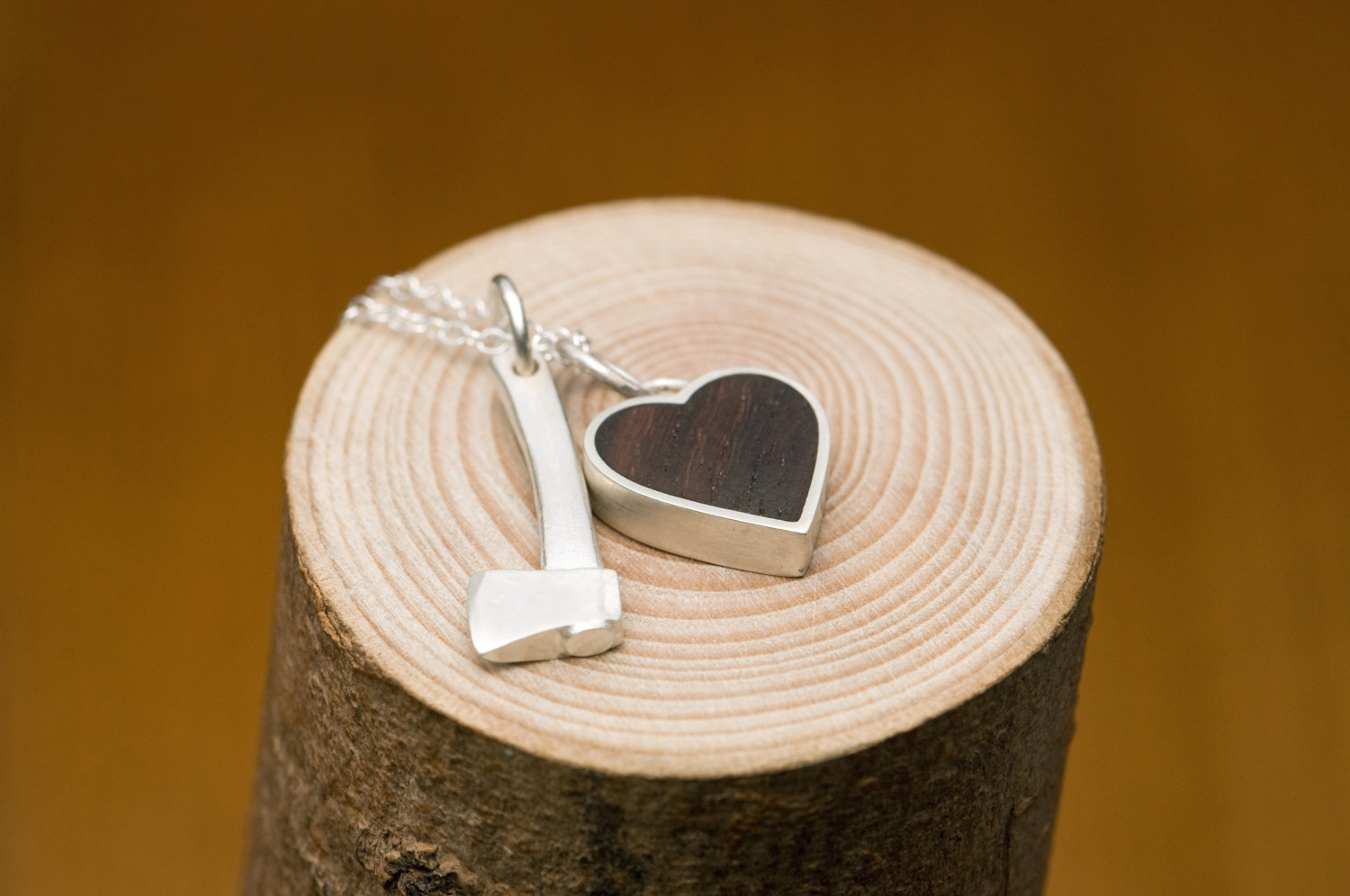 Silver hatchet 'killer charm' and silver heart set with reclaimed rose wood, on a fine silver charm necklace.