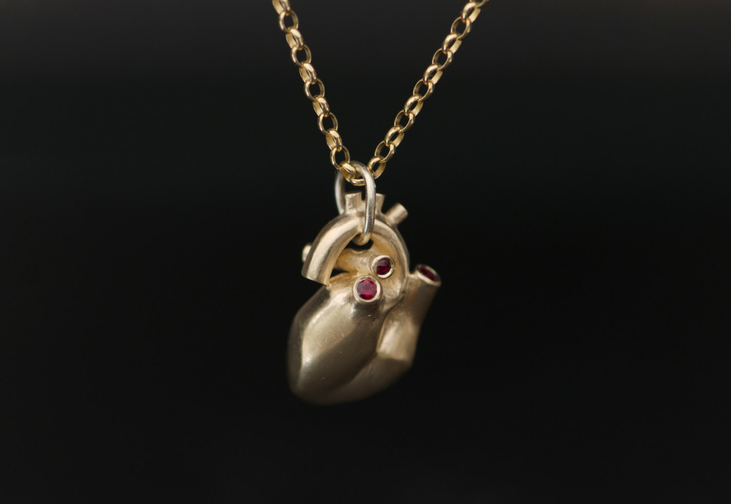 Anatomical heart necklace with 4 small rubies, set in 9K gold. Solid gold heart on a medium weight 9K gold chain. Designed & handmade by William White