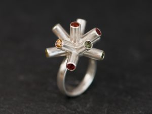 green, red and yellow sapphire particle collision ring in silver