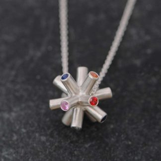 This unique pendant necklace in silver is set with 14 blue, pink, orange, red and green sapphires. Designed and handmade by William White inspired by CERN